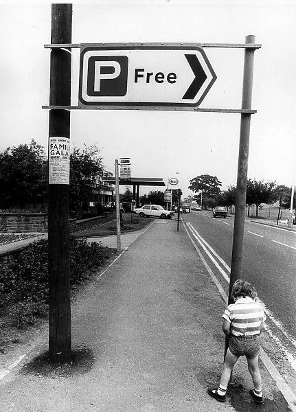 A little boy peeing by a car park sign. Circa 1982