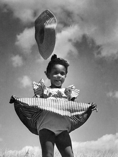Little child wearing candy stripped dress is caught by the wind