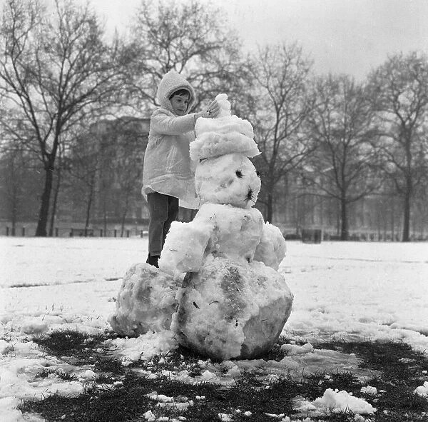 A little girl crowning her snowman in St James Park, London