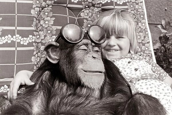 a little girl hugs her chimp friend as they both smile
