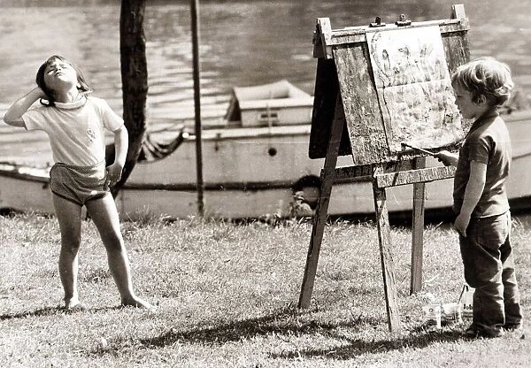 Little girl is posing whilst the young painter gets to work. Circa 1960