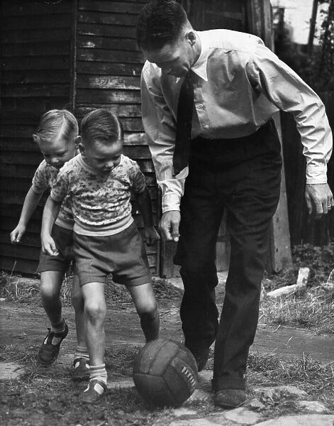 Liverpool footballer Billy Liddell playing football with his twin boys in the back garden