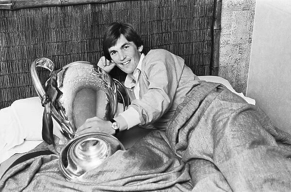 Liverpool footballer Kenny Dalglish poses in bed with the European Cup trophy the day