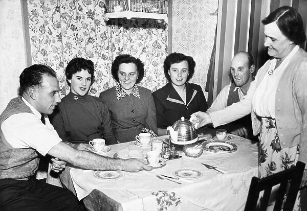 Liverpool full back Ronnie Moran has a cup of tea poured for him bis mother at home