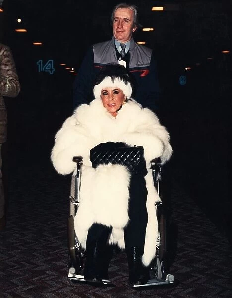 Liz Taylor is pushed through Heathrow airport ijn a wheelchair