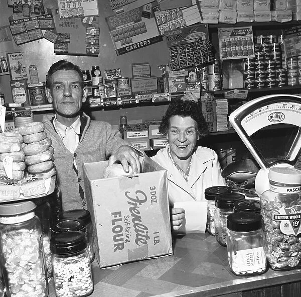 Local grocer and his wife seen here serving a customer. 14th November 1955