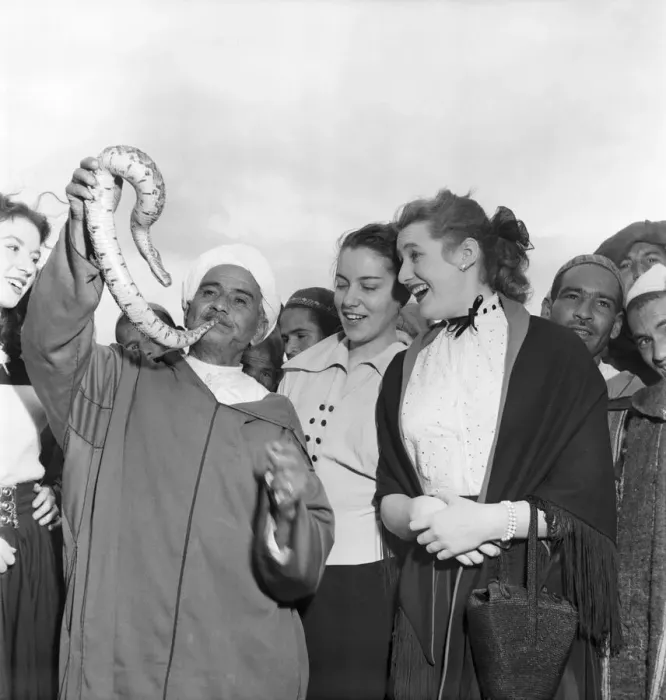 Framed Print : Local man of North Afric holding up a snake with a group of women gathered around to Framed Print : Local man of North Afric holding up a snake with a group of women gathered around to