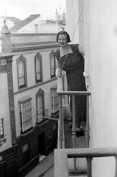 A local woman of Seville, Spain looks out over the town from the balcony of her town