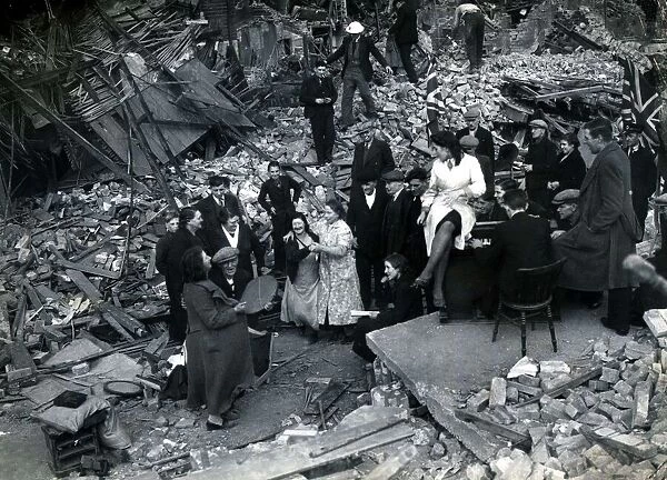 Locals dancing around the piano down Bow way, London. Blitz