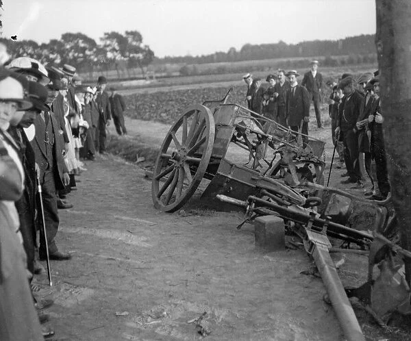 Locals examine a damaged and abandoned gun limber in the remains of the Belgium village