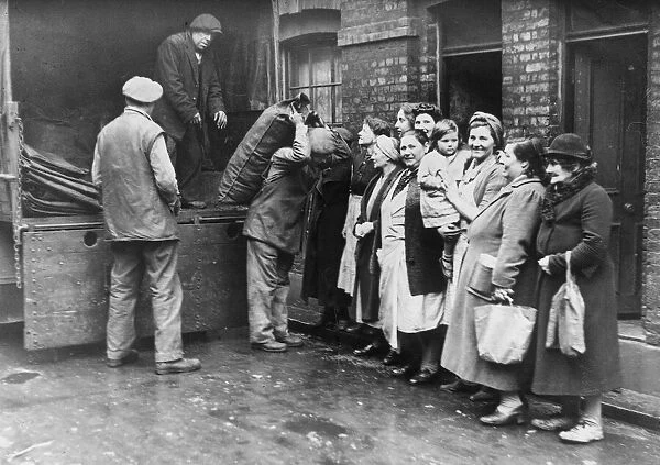 London housewives queue up to receive thier supply of coal from the roundsman
