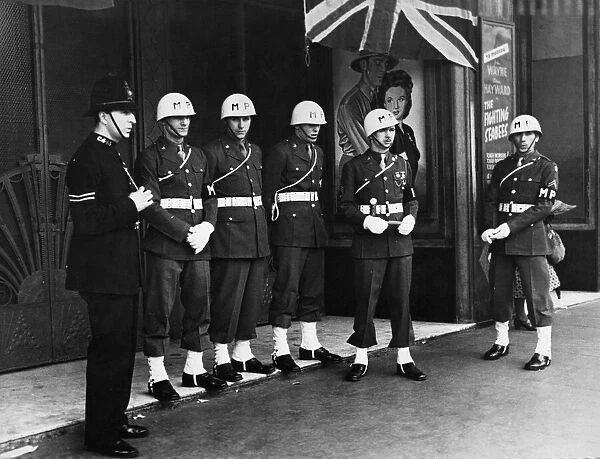 A London sergeant and US Military Police on duty guarding the Royal Cinema in central