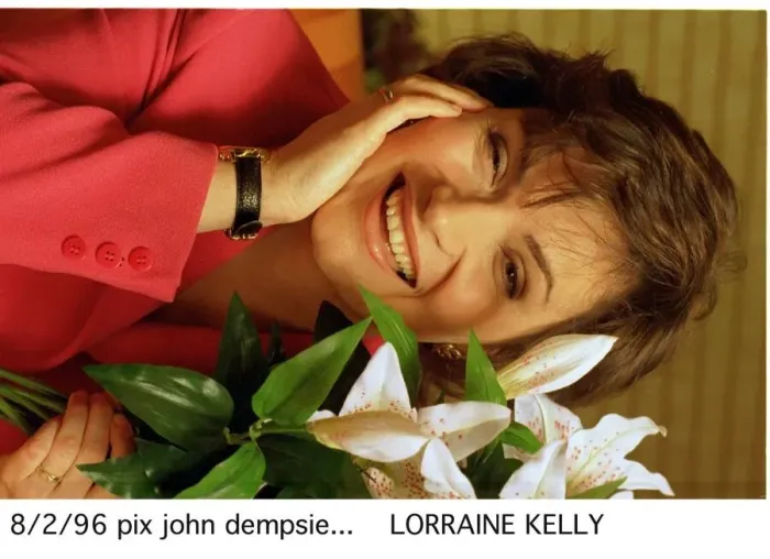Framed Print : Lorraine KELLY next to a green white plant red jacket watch