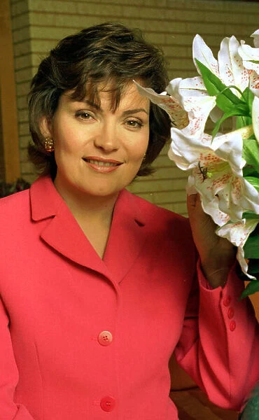 Lorraine Kelly TV presenter wearing a pink suit poses with some flowers