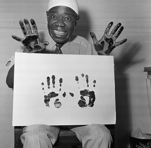 Louis Armstrong, veteran Jazz star, dips his hands in black ink