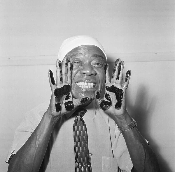 Louis Armstrong, veteran Jazz star, dips his hands in black ink