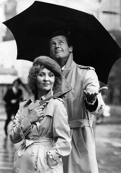 Lulu holding a Dunhill gun and Roger Moore together in the rain outside the Hilton Hotel