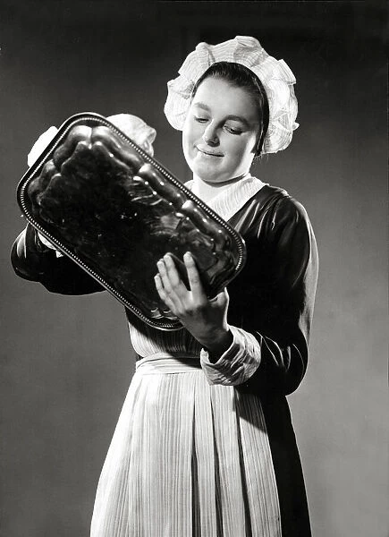 A maid polishing a silver tray, March 1938