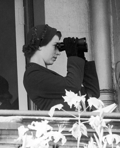 Her Majesty Queen Elizabeth II watching her horse in action through a pair of binoculars