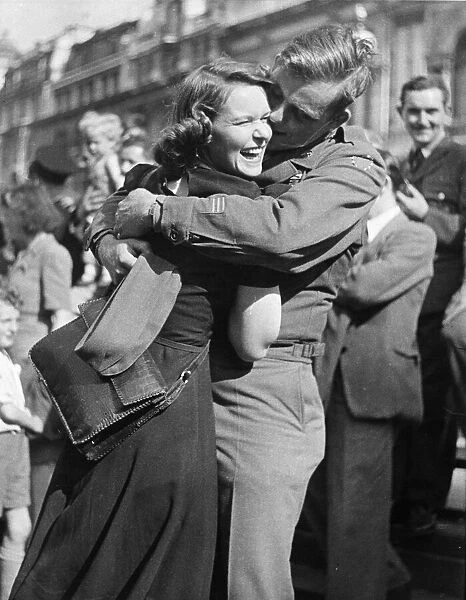 A male and female soldier embrace on hearing the news that Japan has surrenders in World