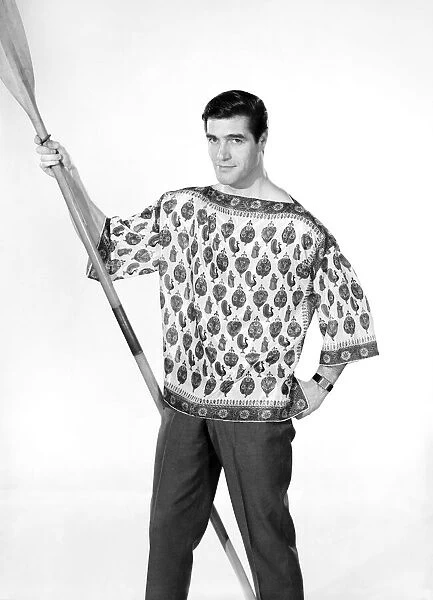 Male model Peter Christian wearing silk shirt seen here holding a oar. Circa 1964
