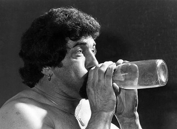 Male Stripper mel blowing into a milk bottle. June 1977 P018599