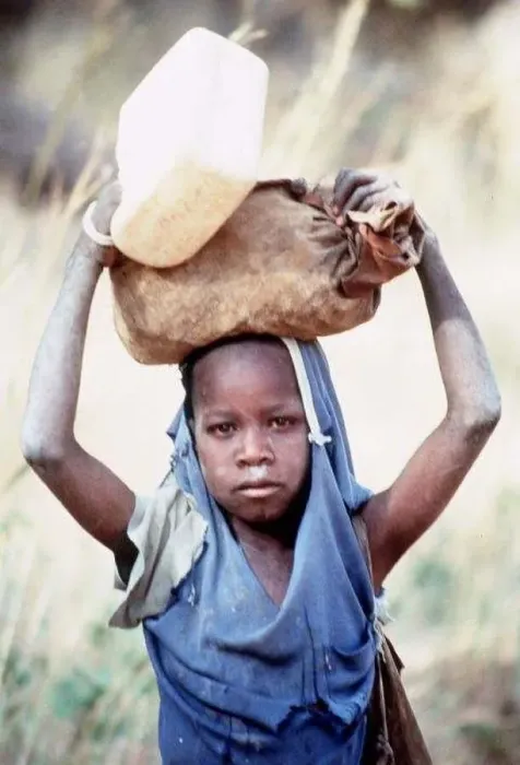 : Mali Dogon Tribe a young girl carrying heavy item on her head : Mali Dogon Tribe a young girl carrying heavy item on her head