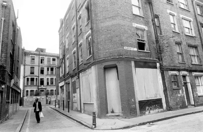 Framed Print : A man carrying his shopping bag as he walks past delapidated buildings with broken Framed Print : A man carrying his shopping bag as he walks past delapidated buildings with broken