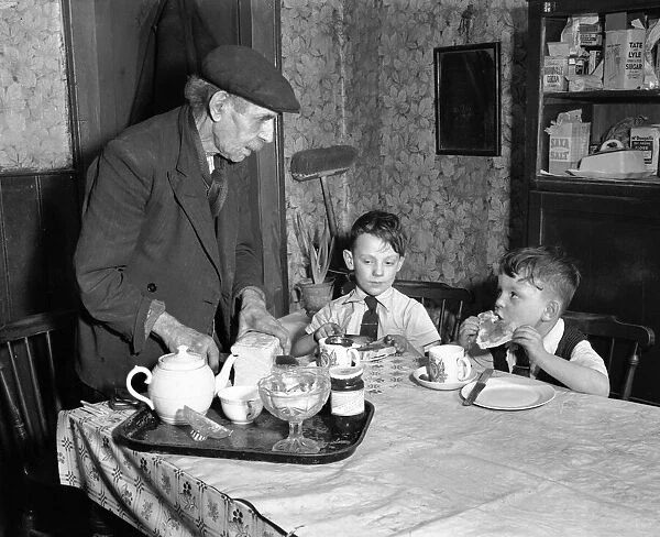A man cutting up a fresh loaf of bread to serve his grandchildren at the breakfast table