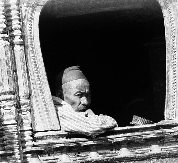 A man deep in thought looks out from a window of a buddhist temple in Katmandu, Nepal