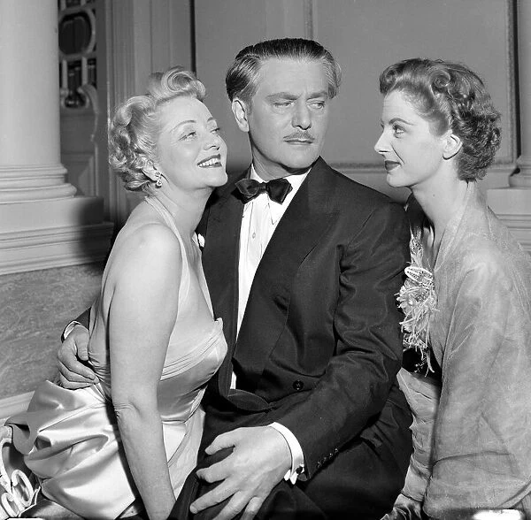 A man dressed in a smart evening suit with bow tie talking to two glamorous women at a