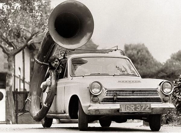 A man driving car with a large Sousaphone attached to the side Musical instruments