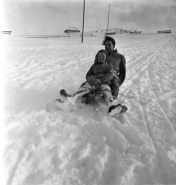 Man and girl on a wooden sledge in the snow at a resort in Switzerland