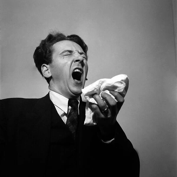 Man holding his handkerchief while sneezing. October 1952 C4925-001