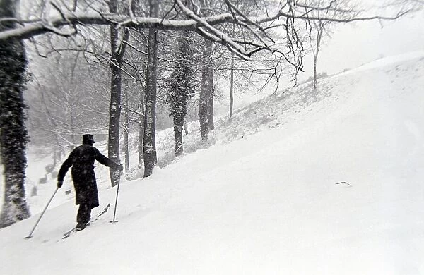 A man making his way to the top of the hill on skis after a heavy snowfall in Boxhill
