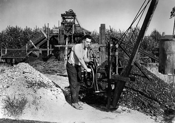 A man operating large piece of equipment at the top of a mine October 1947