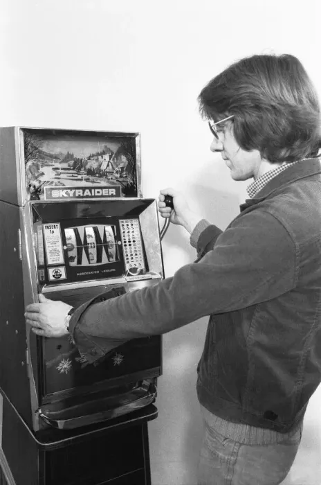 Framed Print : Man playing a one arm bandit slot machine in a London amusement arcade. 8th January 1975 Framed Print : Man playing a one arm bandit slot machine in a London amusement arcade. 8th January 1975