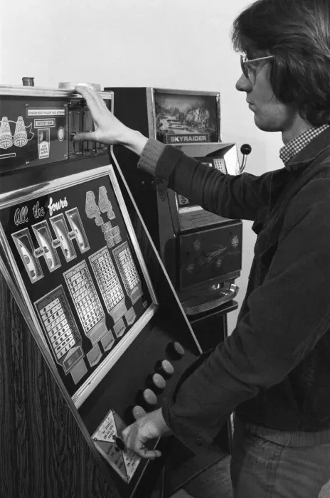 Framed Print : Man playing a one arm bandit slot machine in a London amusement arcade. 8th January 1975 Framed Print : Man playing a one arm bandit slot machine in a London amusement arcade. 8th January 1975