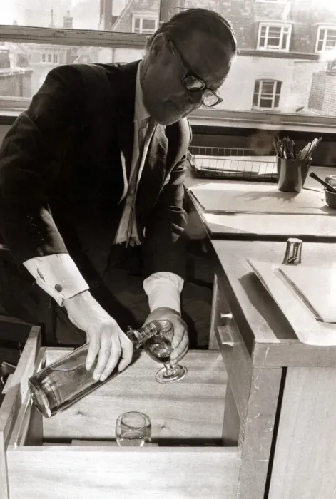 Framed Print : A man pours himself a drink which he keeps hidden in a filing cabinet in his office