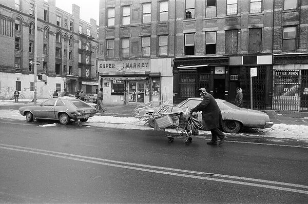 A man pushing a shopping trolley in the road in New York. 13th February 1981