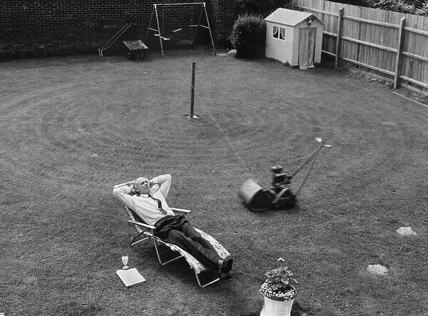A man relaxes in his deckchair as his lawnmower carries on with out him