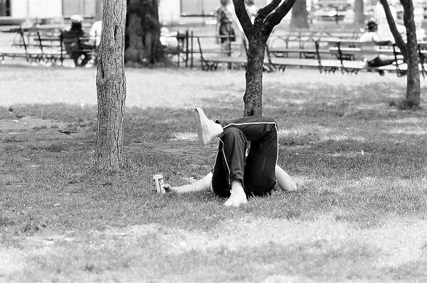 Man relaxes in the park, keeping cool with a can of beer, New York, USA, June 1984