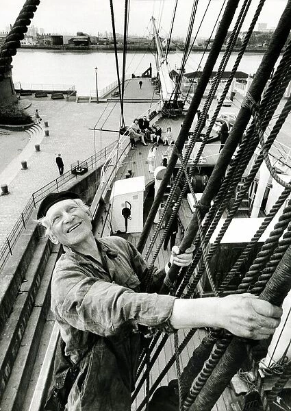 A man of the sea perched high above the deck of the Cutty Sark returns the wave to two