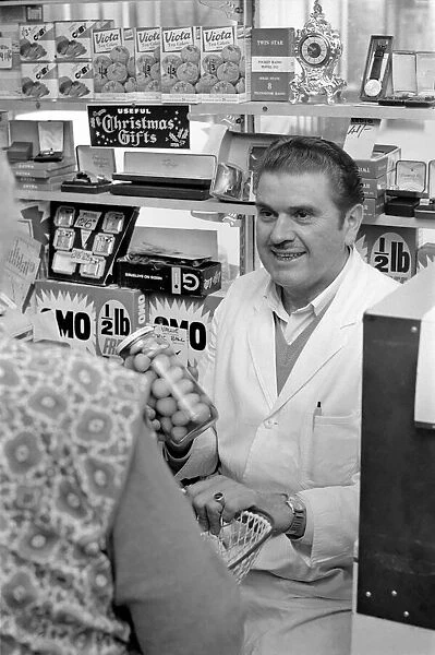 A man serving a customer in his shop at Deptford. November 1969 Z10715-004