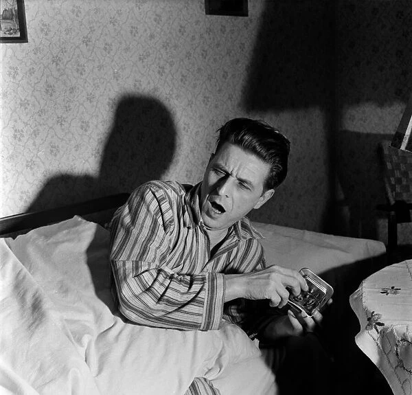 Man setting alarm clock before going too bed. December 1952 C6101-014