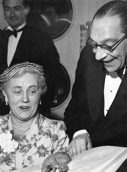 Man showing off a chicken drumstick to a woman at a dinner party Circa 1955