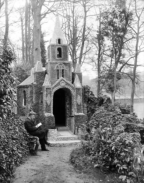 A man sitting on bench reading outside The Church of Shells, called La Grotte
