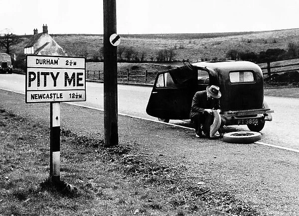 A Man trying to repair a punctured tyre outside the Hamlet of PITY ME in Durham county