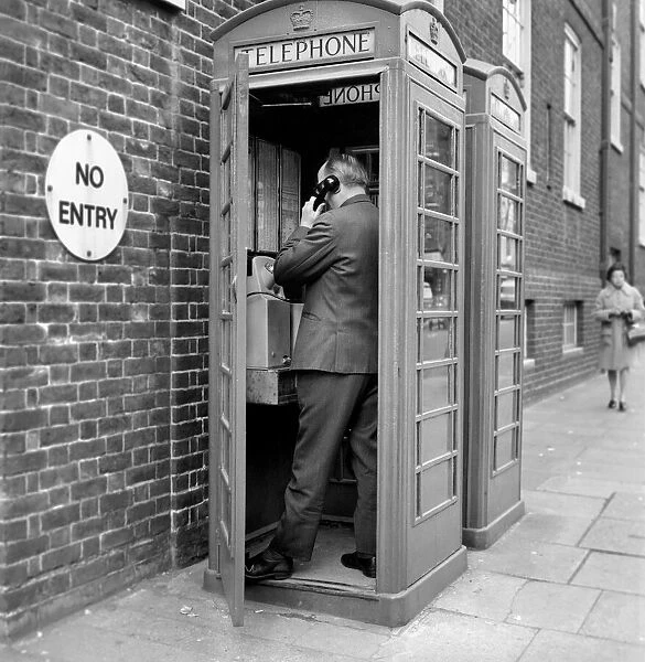 Man using a telephone box. The red telephone box was designed by Sir Giles Gilbert Scott