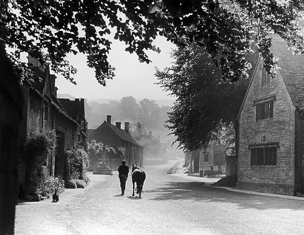 A man walking along a country lane with his pony in Stanton, a typical Costwold village